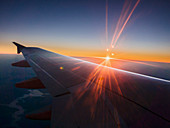 Sunset behind airplane wing in sky