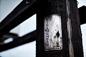 Rusted metal sign on telephone post