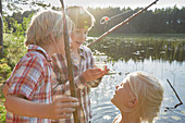 Brothers and sister fishing at sunny pond
