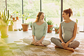 Smiling pregnant women talking on rug