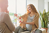 Pregnant woman receiving gift from friend