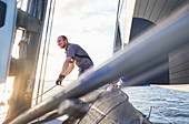 Man sailing holding rigging on sailboat