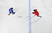 Hockey players going for puck on ice