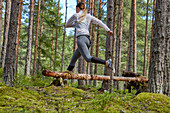 Runner jumping over fallen log in woods