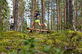 Runner jumping over fallen log in woods