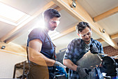 Metal workers using sander in workshop