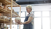 Senior woman placing vase on shelf