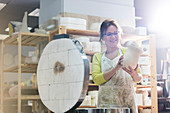 Mature woman placing pottery vase in kiln