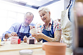 Senior couple painting pottery in studio