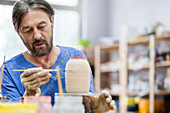 Mature man painting pottery vase