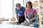 Mature couple using pottery wheel