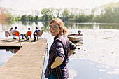 Smiling woman at sunny lakeside dock