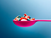 Medicine capsules in pink spoon
