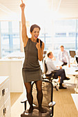 Businesswoman celebrating on top of office chair