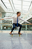 Businessman skateboarding in office corridor