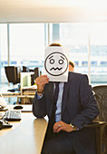 Businessman holding frowning face printout