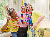 Mature adults dancing with leis in living room