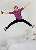 Man jumping on bed with legs apart