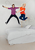 Couple jumping on bed and listening to music