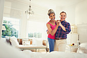 Portrait smiling mature couple dancing in bedroom