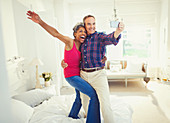 Mature couple taking selfie standing on bed