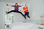 Couple jumping on bed and listening to music