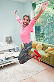 Portrait Mature woman jumping in living room