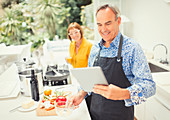 Mature couple with digital tablet cooking