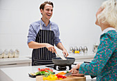 Couple cutting and cooking vegetables in kitchen