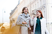 Smiling women carrying shopping bags in city