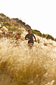 Man running through tall sunny grass