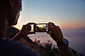 Man photographing sunset ocean view