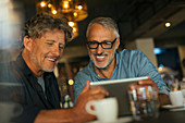 Men using digital tablet at restaurant table