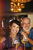 Portrait smiling couple drinking white wine in bar