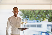 Waiter serving white wine on tray