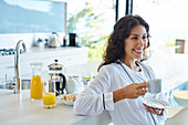 Smiling woman in bathrobe drinking coffee