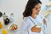 Smiling woman in bathrobe drinking water