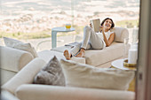 Woman reading book relaxing on chaise lounge