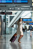 Businesswoman rushing pulling suitcase