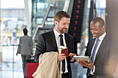 Businessmen with digital tablet talking in airport
