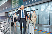 Businessman talking on cell phone pushing suitcase