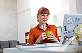 Smiling woman drinking coffee and working