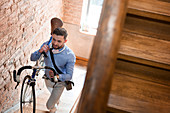 Man carrying bicycle up stairway