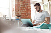 Man using laptop on bed in apartment