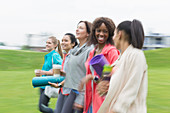 Smiling friends walking with yoga mats and coffee