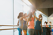 Women high fiving in sunny gym studio