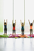 Women on cushions stretching with arms raised