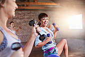 Smiling young women with dumbbells