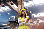 Female steel worker with walkie-talkie in factory