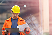 Steel worker reviewing blueprints in factory